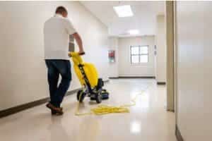 A man is cleaning the floor with a yellow machine.