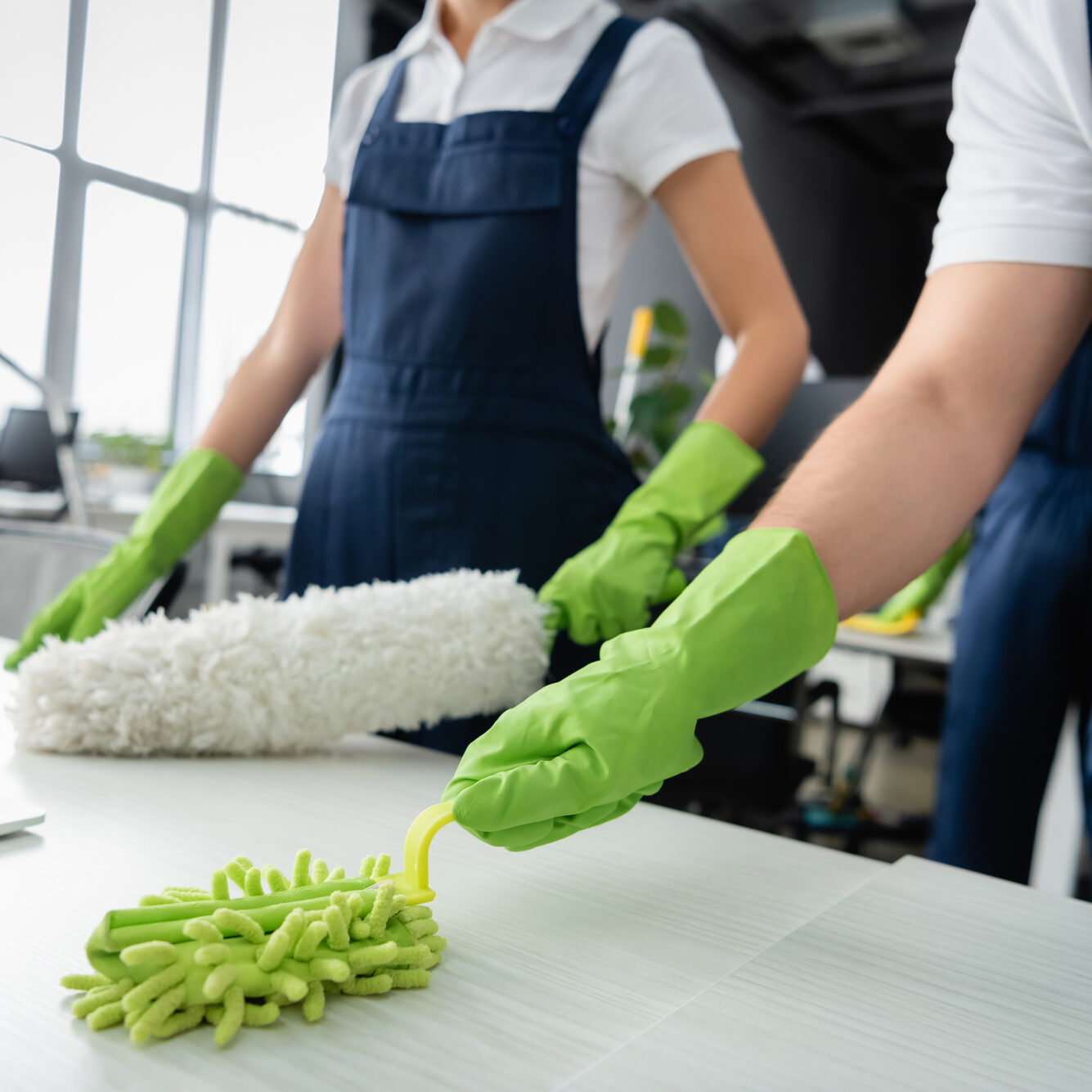 Gulf South Janitorial employees with green gloves dusting an office