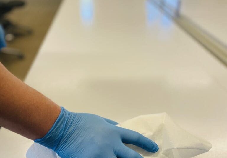 A person wearing blue gloves while office cleaning for Gulf South Janitorial