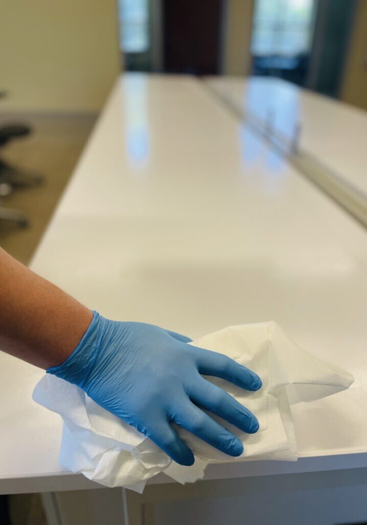 A person wearing blue gloves while office cleaning for Gulf South Janitorial