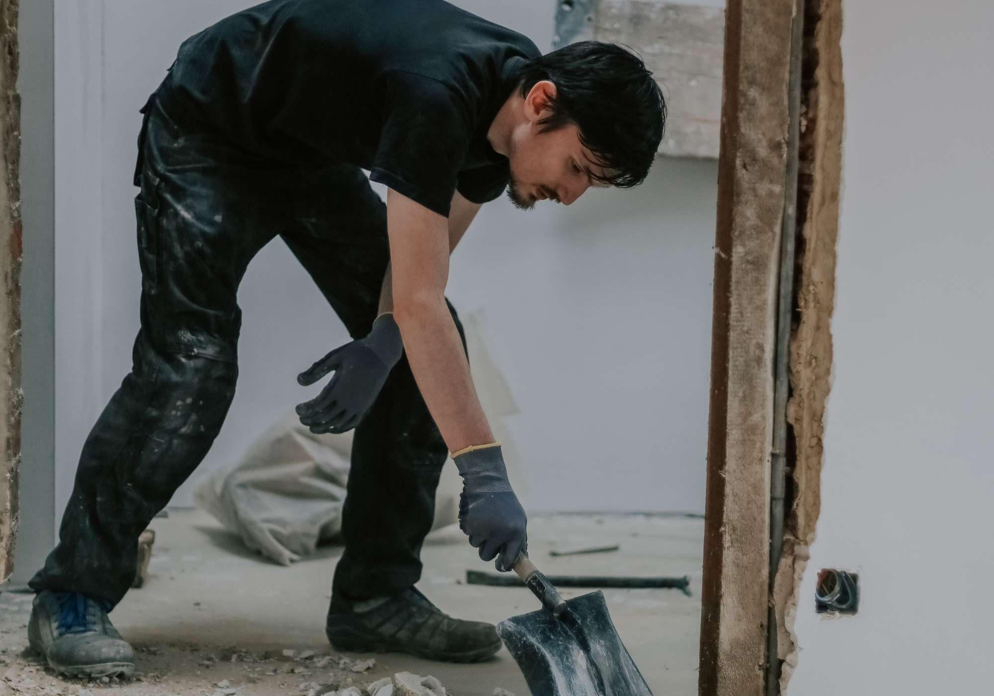 A gulf south janitorial technician in black shirt and gloves digging.