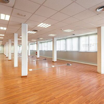 A large room with many windows and wooden floors.