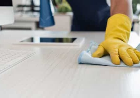 A employee of Gulf South Janitorial in yellow gloves cleaning the floor.